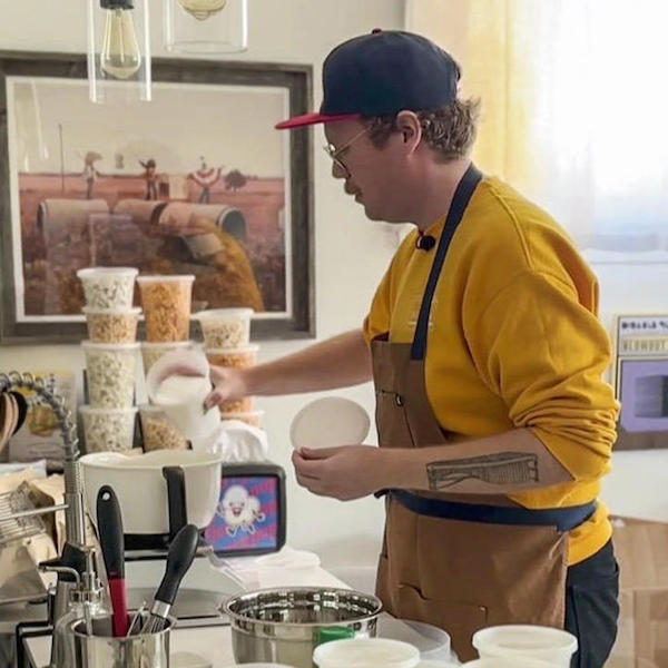 Photograph of Jerry pouring salt into a batter bowl during craft popcorn production.